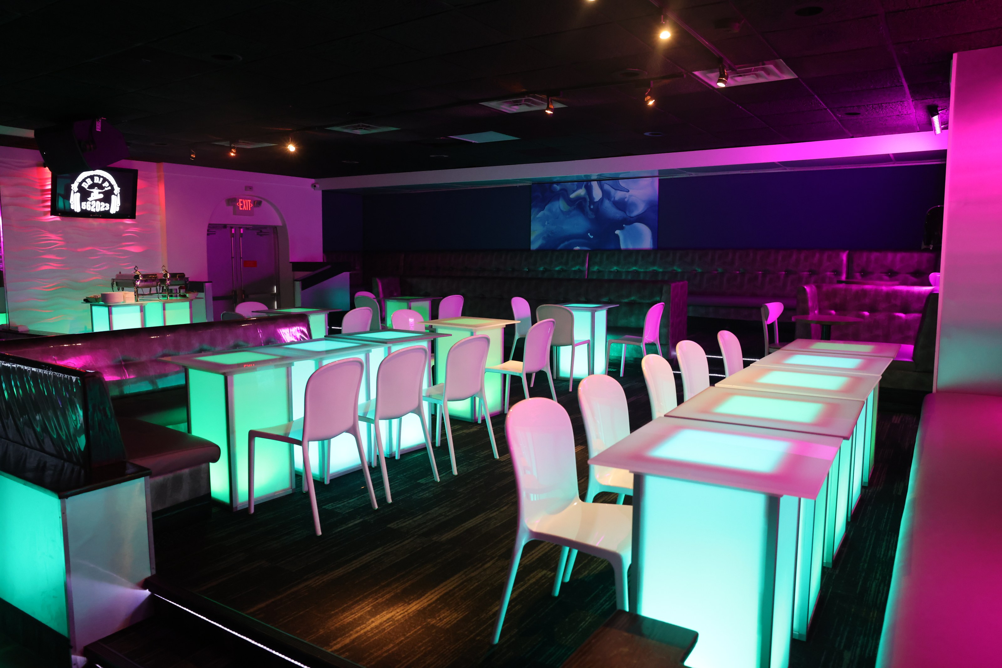A prepared event room with illuminated tables and lounge seating